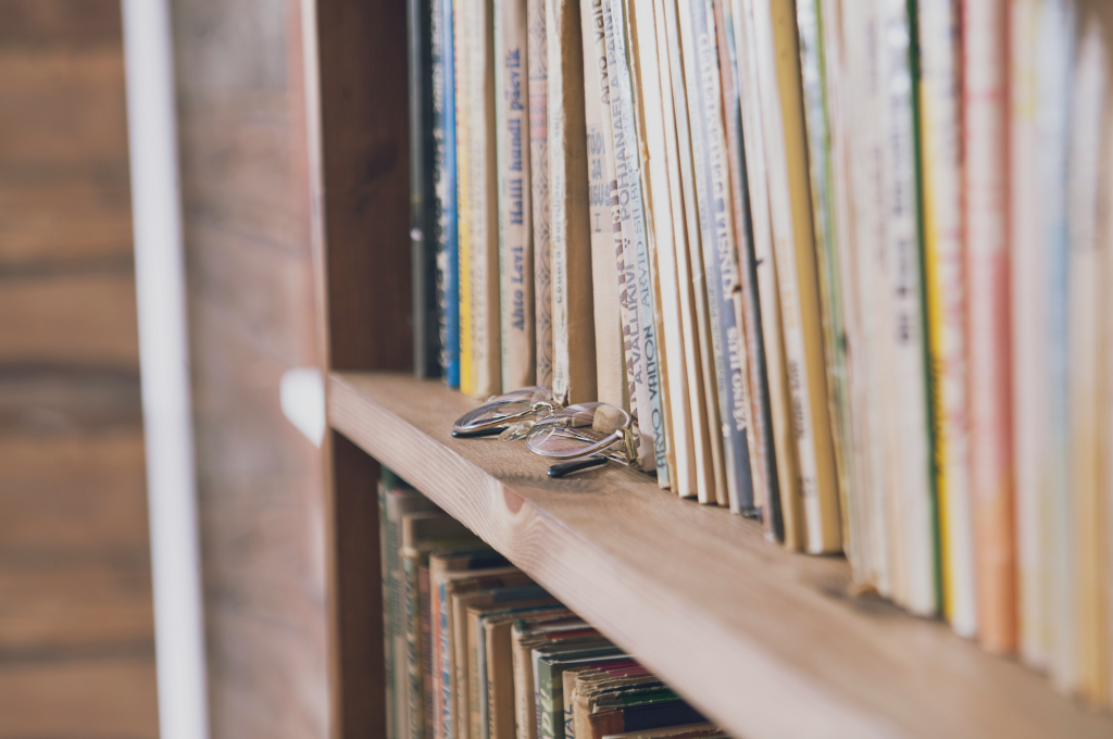 Books and pair of glasses sitting on wooden shelf